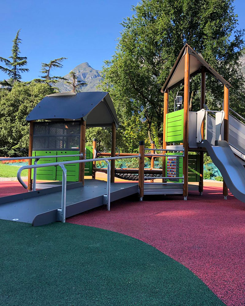 Side view of a playground unit which has an accessible ramp leading to the entrance of the playground unit.